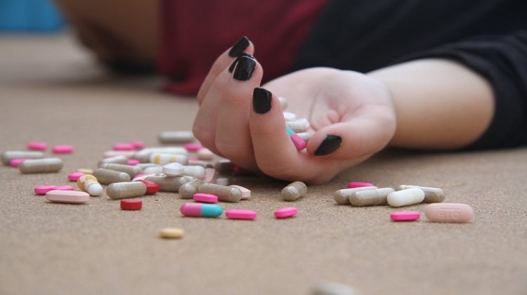 Woman's Hand on table, with lots of pills. - 4 Tips for Dealing with Drug Rehabilitation as a Family