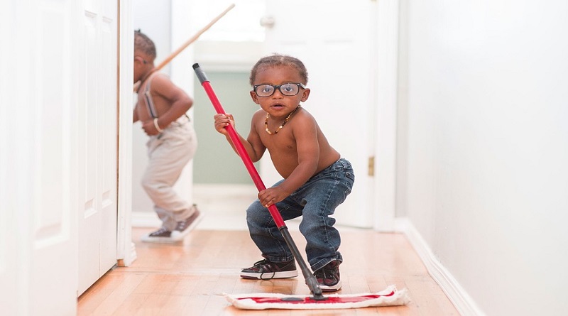 Adorable little boy helping to mop wood floor -