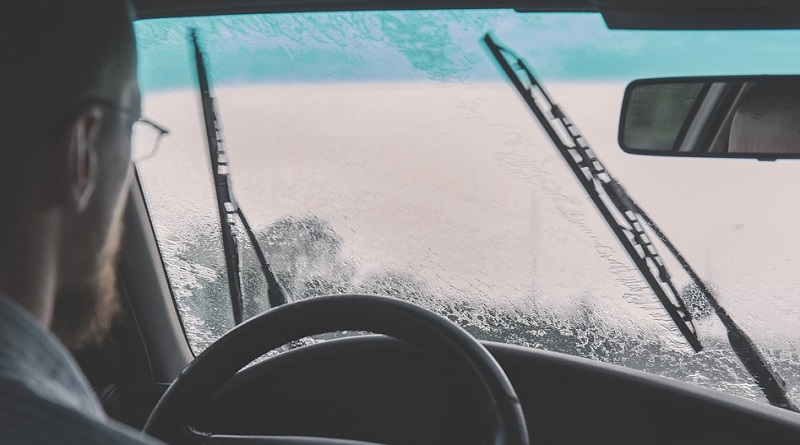 Man driving his car in the rain using windshield wipers - Wiper Blades