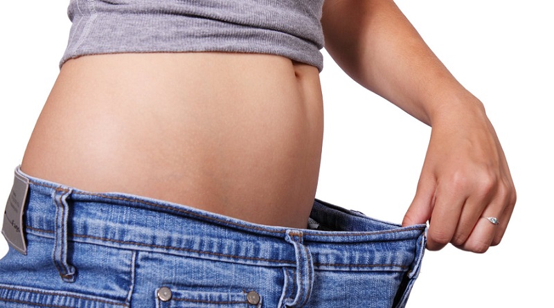 Woman holding waistband out from her belly - Safe Ways To Lose Weight