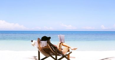 Woman reading in lounge chair on beach - Signs You Need a Holiday