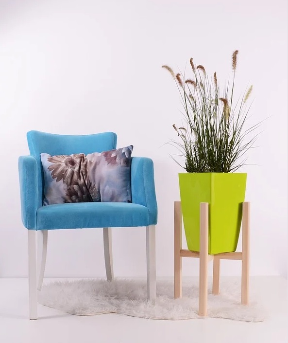 Blue chair with floral pillow and plant stand with bright green pot with plant - If Your Home Is Stressing You Out