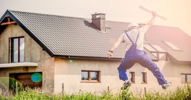 Man in overalls holding building plans, jumping in air in front of house - Your Dream Home