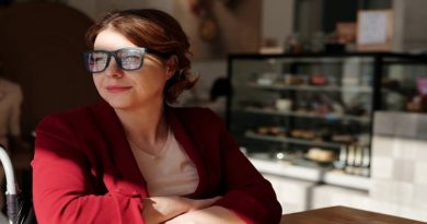 Woman wearing glasses, a pink shirt, and red jacket - Feel More Alert