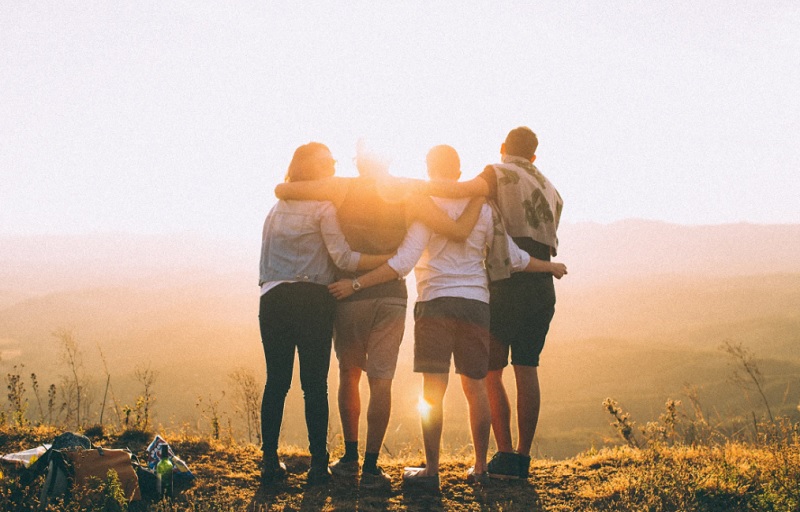 Friends together on a mountaintop at dawn - Is It Time To Make New Friends?