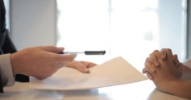 Man holding pen and paper across desk -Everything You Need To Know About Mortgages