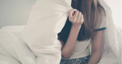 woman sitting on edge of bed holding comforter over her head - Remedies for Insomnia