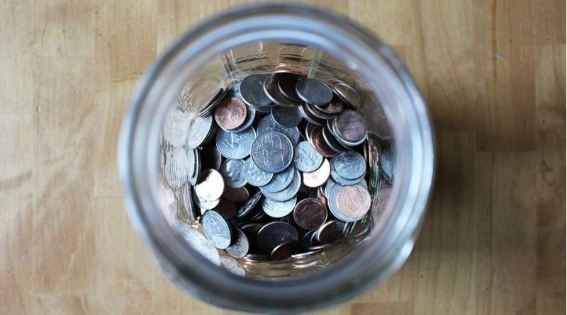 Ways of Saving Money in and Around the Home Jar full of coins on a wood table