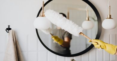 Person wearing rubber gloves dusting a mirror