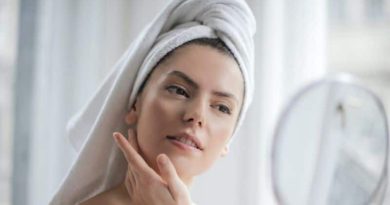 Common Skin Problems Woman wearing no makeup and with her hair wrapped in a towel looking into a mirror