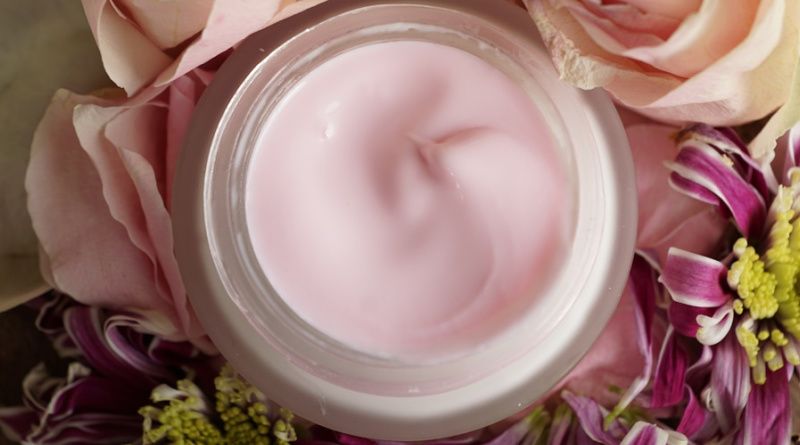 Jar of pink cream surrounded by beautiful flowers