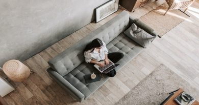 Working Remotely Woman sitting on Grey Sofa working on Laptop