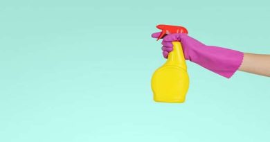 Hiring A Cleaning Company Gloved hand holding bright yellow spray bottled