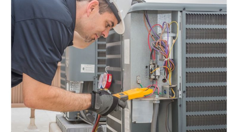 How to Find an HVAC Contractor HVAC repairman reading volt meter on HVAC Unit