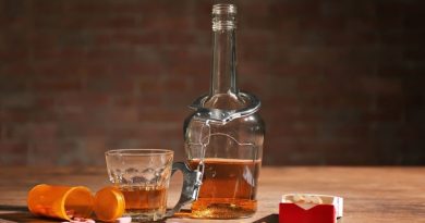 Harmful Interactions Open bottle of pills and bottle of alcohol with a pair of handcuffs