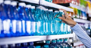 Woman taking disposable bottle of water off of grocery store shelf