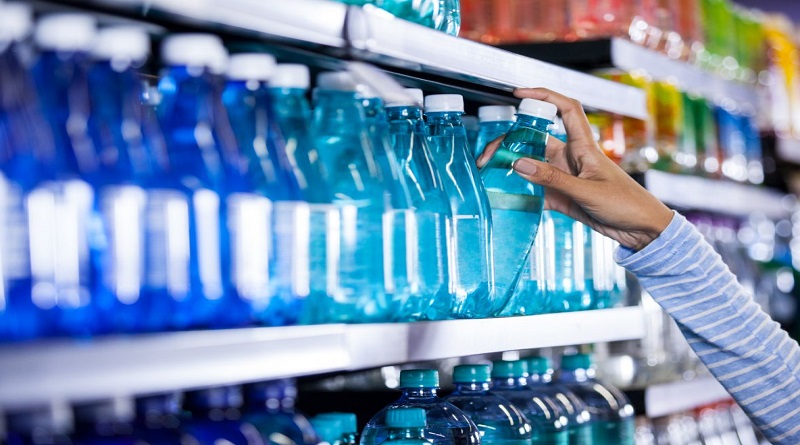Woman taking disposable bottle of water off of grocery store shelf