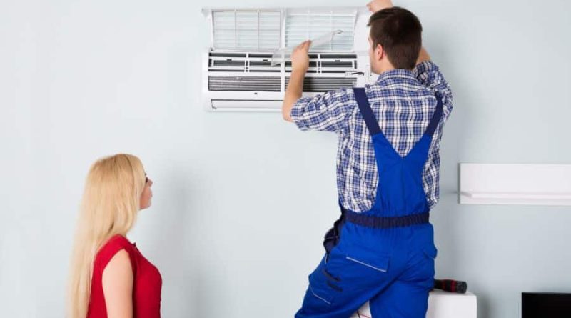 Woman in red dress watching repairman work on AC split unit