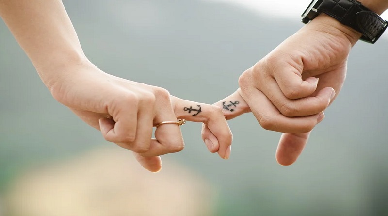 Getting Your First Tattoo Couple with matching anchor tattoos on their fingers