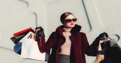Woman in coat and sunglasses holding multiple shopping bags