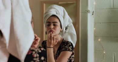 Personal Grooming Hacks Women with her hair up in a towel, looking into a mirror and applying product to her lips