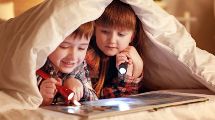 Makes It Simple for Kids to Love Reading / Boy and Girl under Blanket Reading with Flashlights
