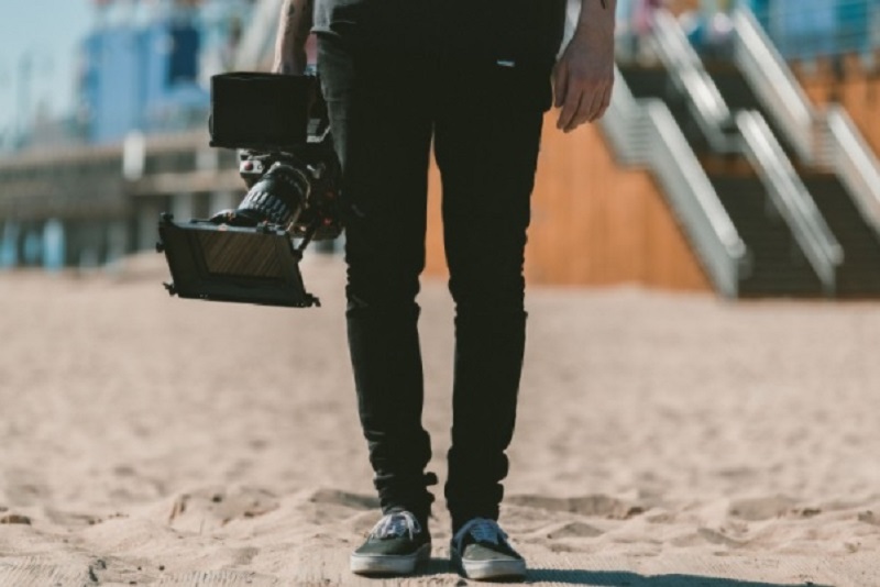 Man on beach holding large video camera / How To Make Your Video Marketing Strategy Stand Out?