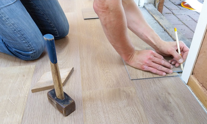 Person with pencil marking flooring for installation / Save More Money On Your Home Repairs