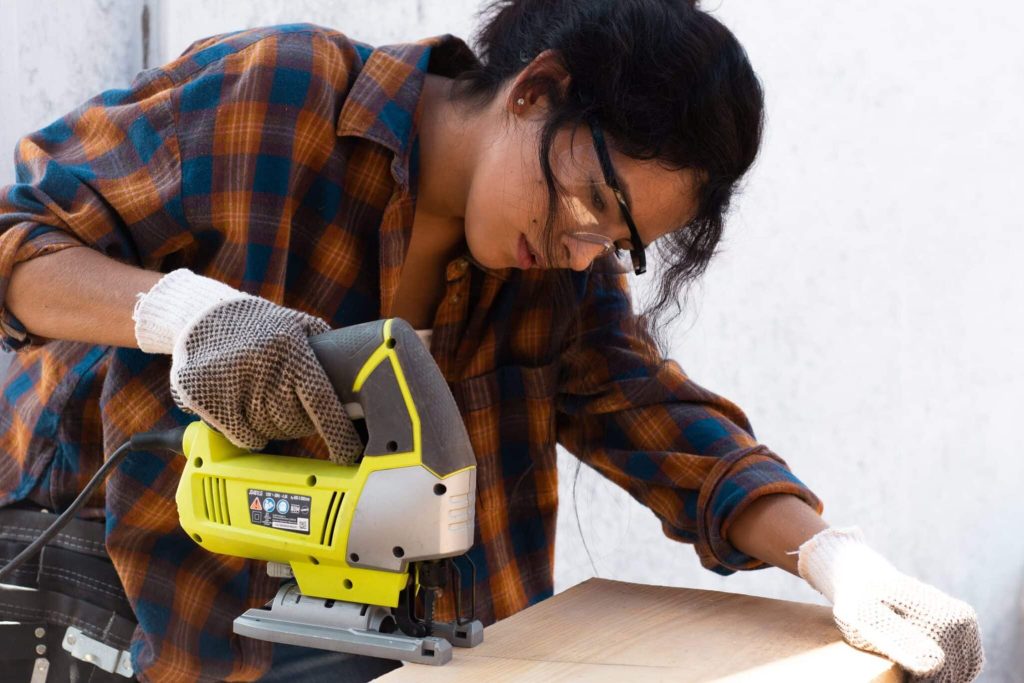 Woman cutting wood with jigsaw