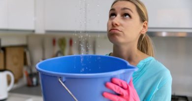 Woman holding bucket under leak in ceiling