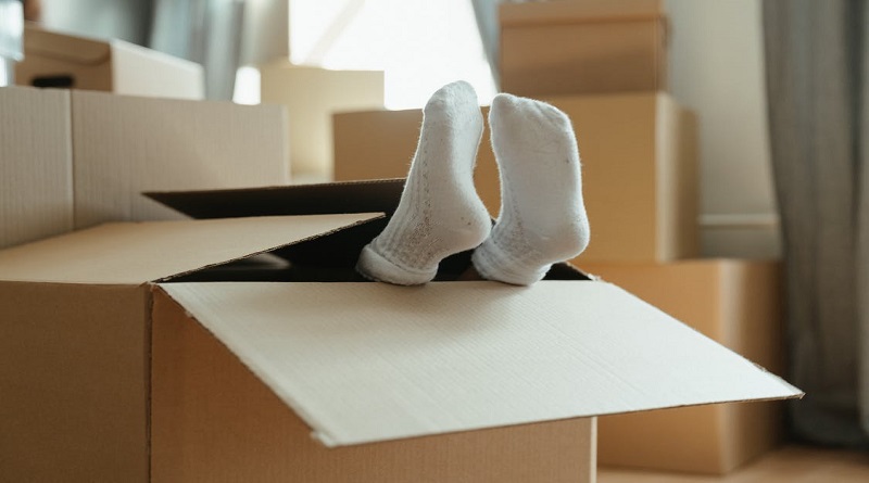 Guide to House Moving Costs / someone in a moving box with their stocking feet sticking out