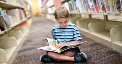 How to Get a Bookish Child Into Sports / Boy reading a book on the floor in a library