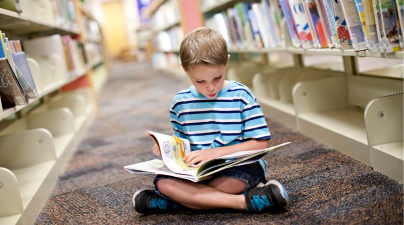 How to Get a Bookish Child Into Sports / Boy reading a book on the floor in a library