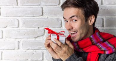 Christmas Gift Ideas / Smiling Guy wearing a sweater and scarf holding a wrapped gift
