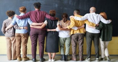 Finding an Inclusive Environment / A diverse group of people with arms linked standing facing a blank chalkboard