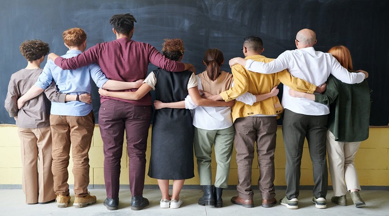 Finding an Inclusive Environment / A diverse group of people with arms linked standing facing a blank chalkboard