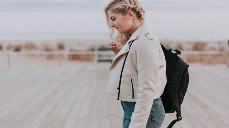 Essential Gear and Equipment You Need for Your Next Trip / Woman in jeans and a jacket carrying a travel backpack
