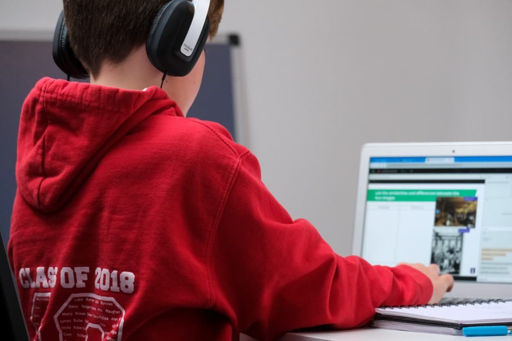 Protecting Your Child's Privacy Online / Child in red hooded sweatshirt with headphones on a laptop