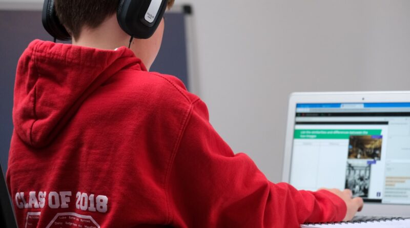 Protecting Your Child's Privacy Online / Child in red hooded sweatshirt with headphones on a laptop