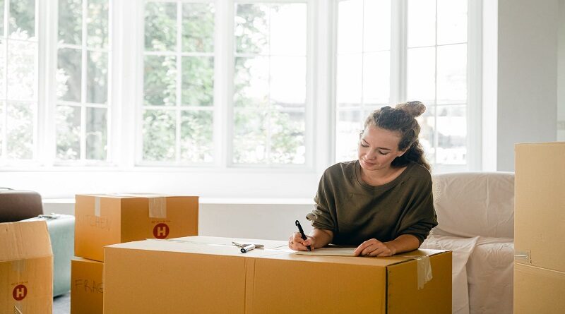 Make Moving to a New Property a Breeze / Woman writing a list surrounded by packing boxes