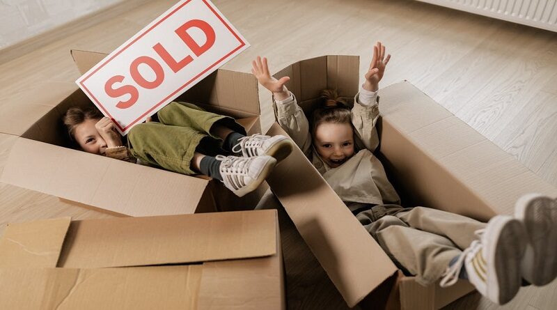 Relocate With Your Family / children playing in empty packing boxes with one holding a sold sign