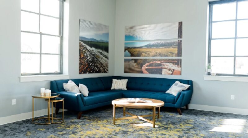 Make Your Home More Stylish / Bright and airy living room with 2 large windows a blue sectional sofa and large prints on the walls