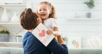 Dad hugging his smiling little girl who is holding a Father's Day card