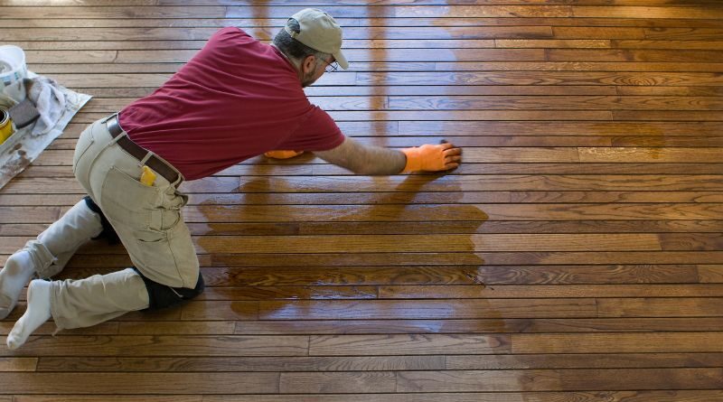Renewing or Refinishing Old Hardwood Floors / man working refinishing a hardwood floor