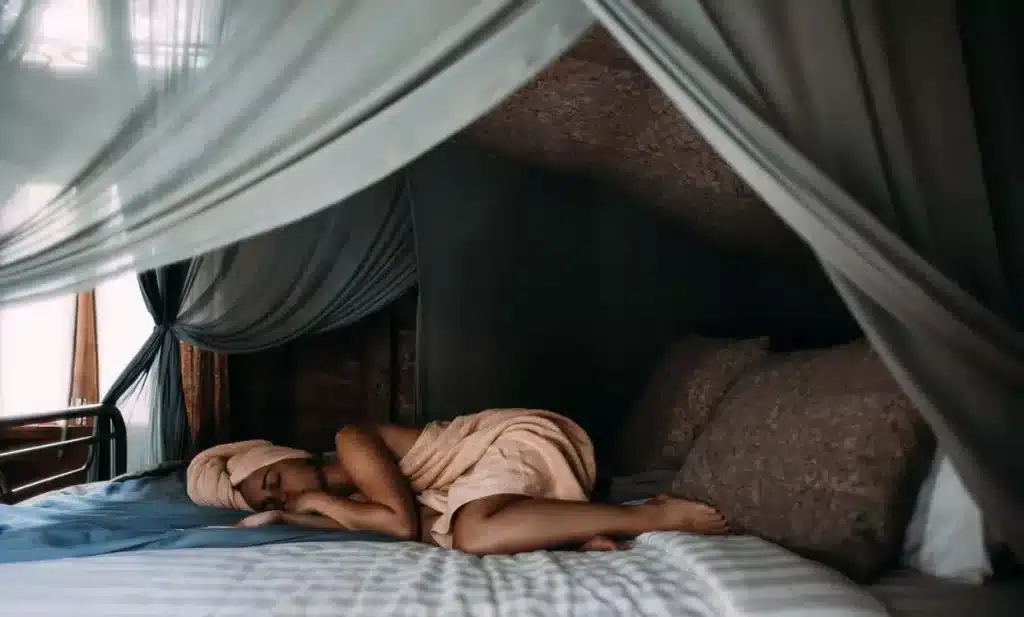 Improving Your Health / woman wrapped in towel sleeping on bed with a large canopy