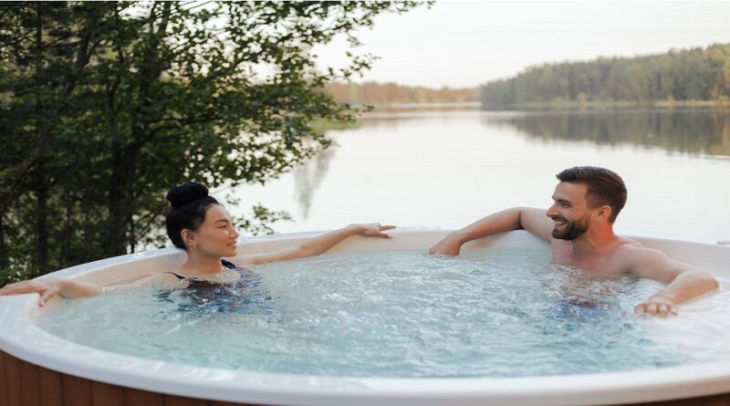Hot Tub Maintenance / Couple relaxing in a hot tub with a beautiful view of a peaceful lake