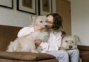 Tips For Keeping Your Pet Healthy / Woman on sofa snuggling with her two dogs