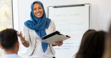 Ways To Create A Safe Workplace For Employees / Lovely Woman in Blue Head Covering Teaching a Training Class in an Office