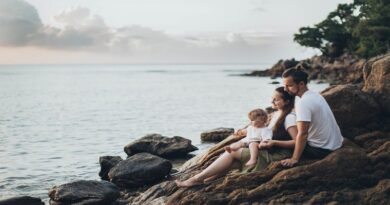 How to Plan and Execute a Successful Family Trip / Man woman and small child sitting on rocky seashore