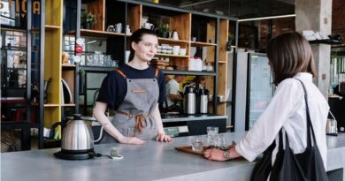 Woman in a Black Shirt and Grey Apron waiting on a customer in a coffee shop /4 Strategies to Boost Sales in Your Small Business